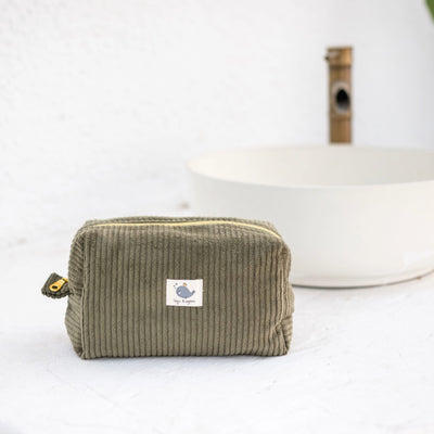 Green corduroy pouch with a small label on a white surface
