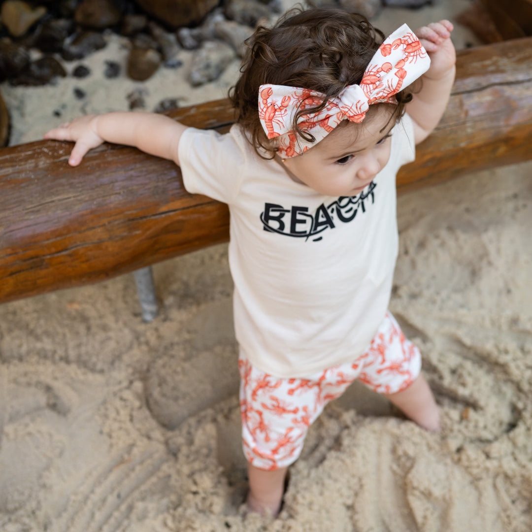 Child standing on a sandy playground with wooden equipment