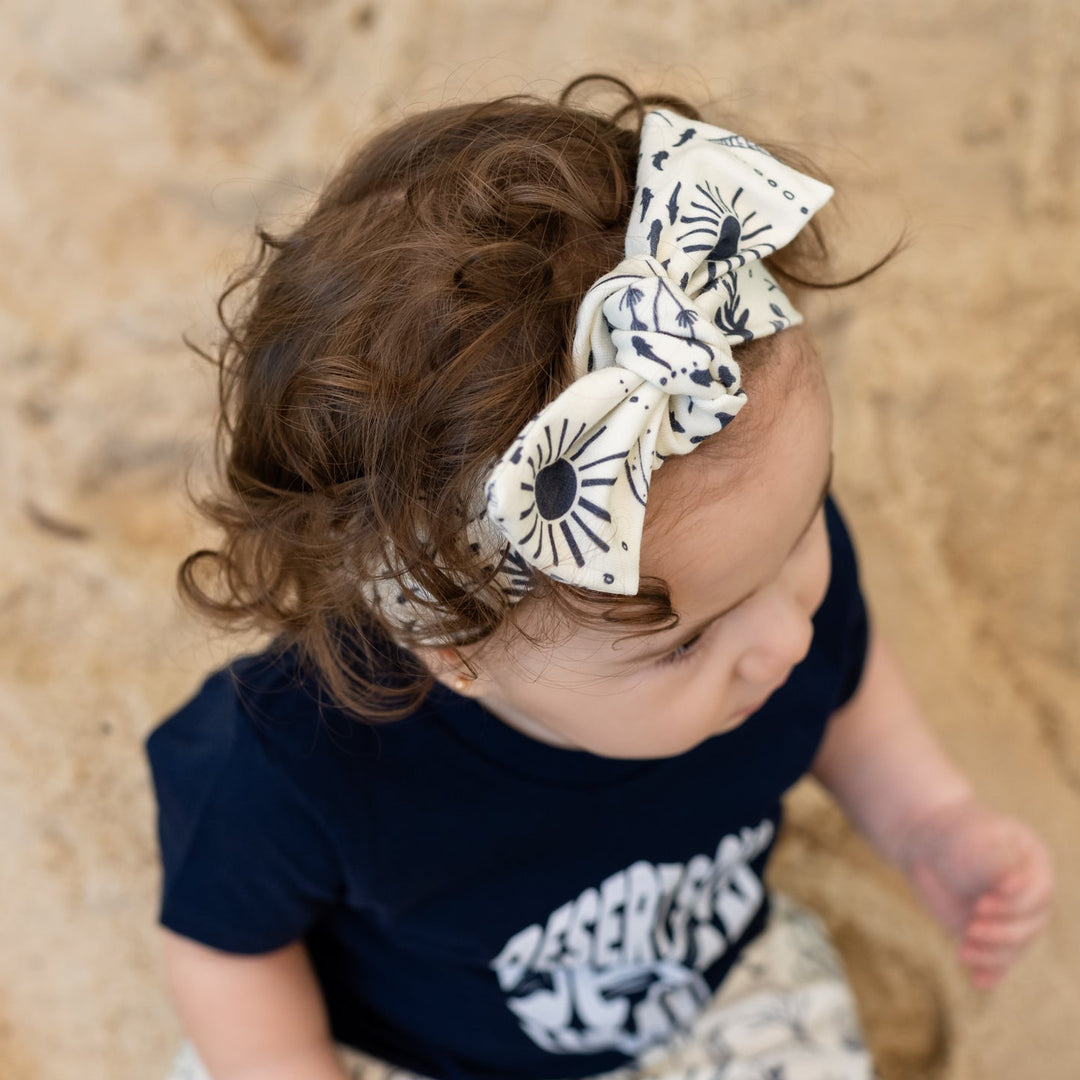 Baby in navy outfit with ocean scene headband and haram pants on sandy background