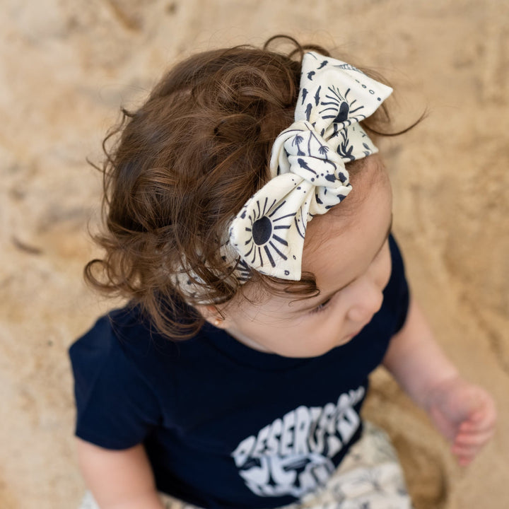 Baby in navy outfit with ocean scene headband and haram pants on sandy background