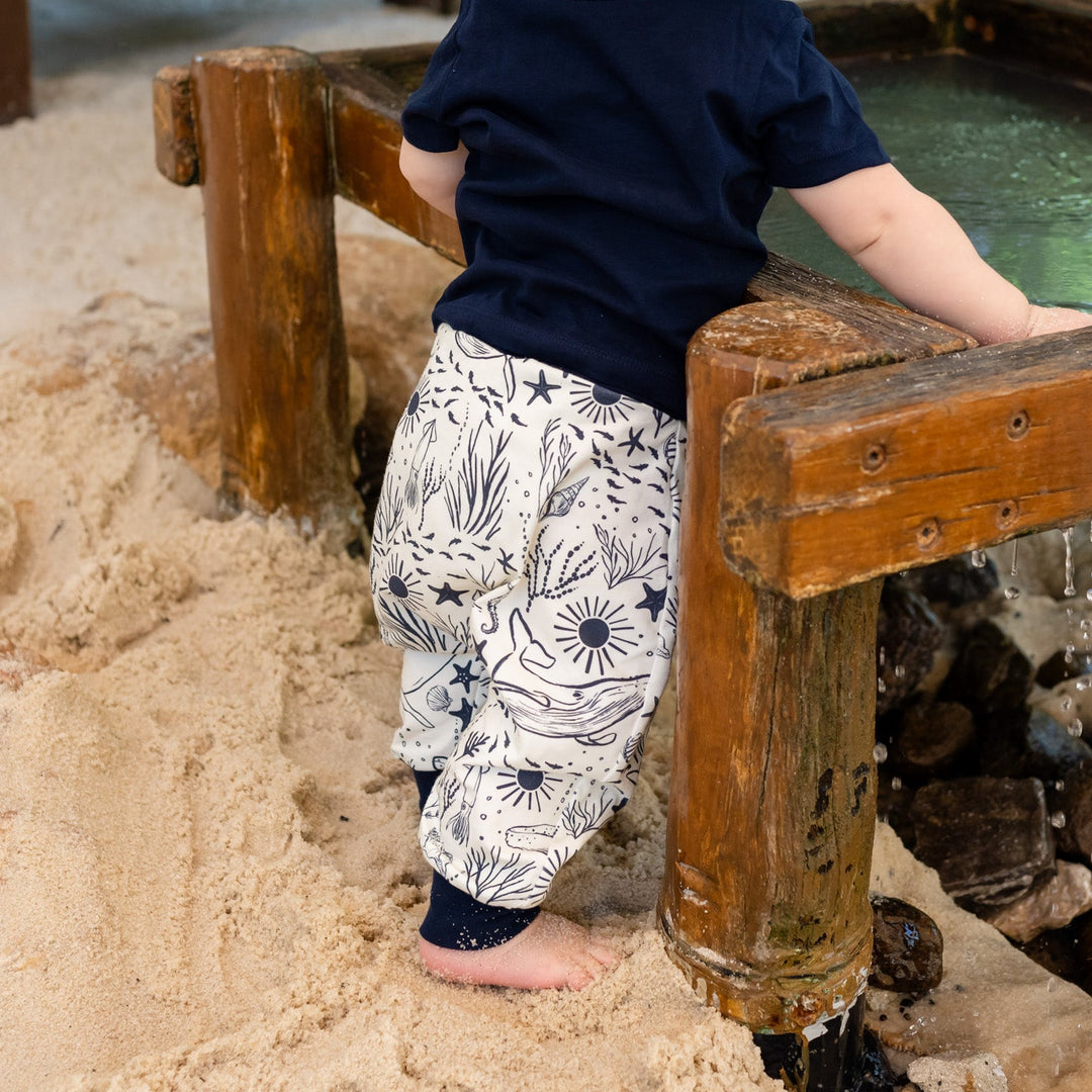 Child playing in a sand pit with wooden structures. wearing haram pants