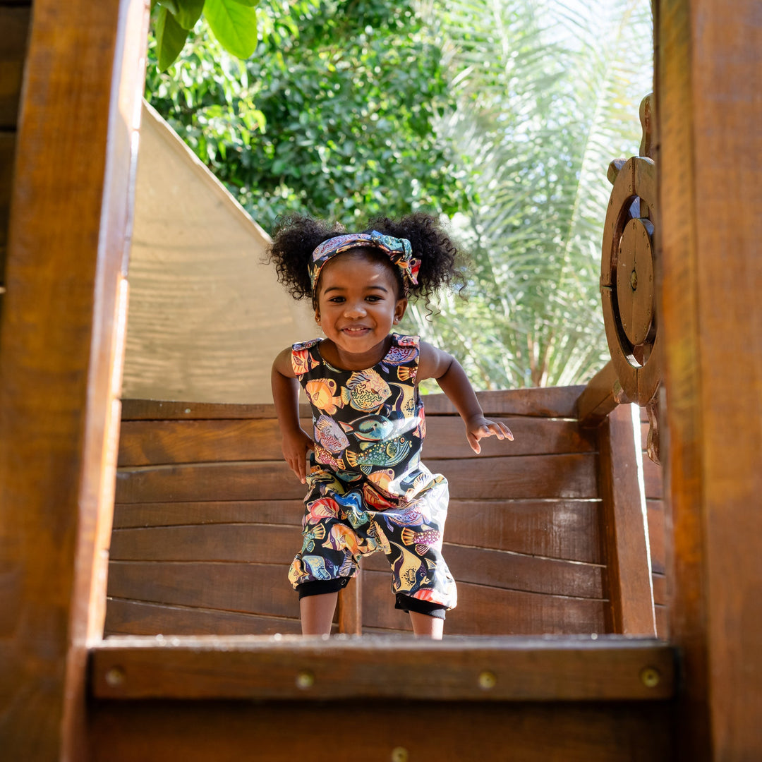 Child standing inside a wooden playhouse with a natural background