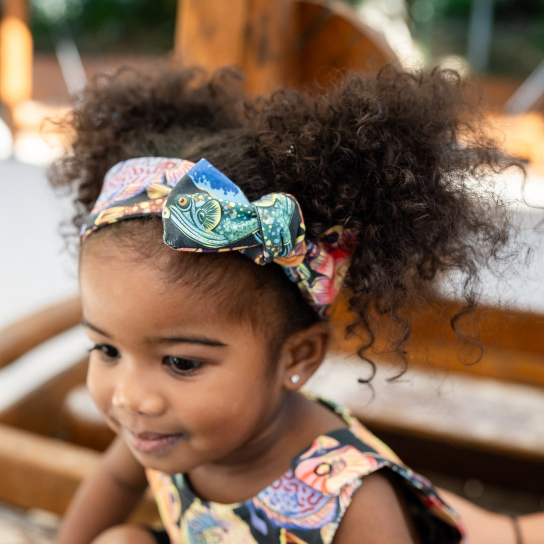 Young child with a colorful headband sitting outdoors