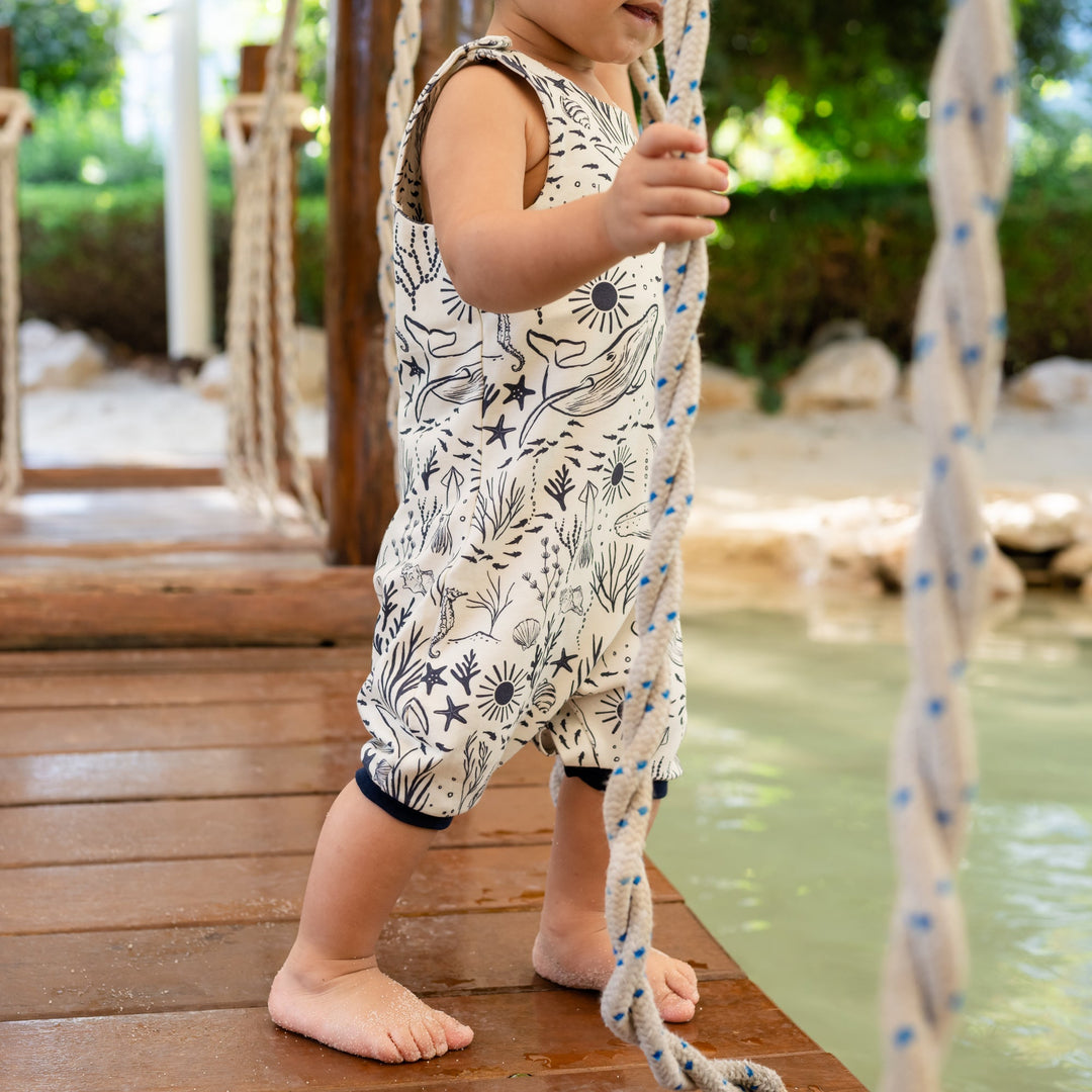 Child standing on a wooden platform by a pool with a swing set in the background