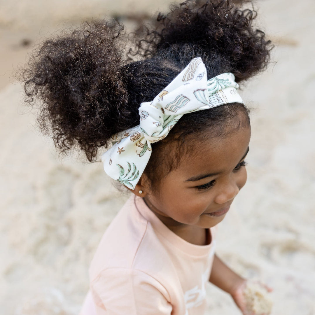 Child playing in sand with a beach life headband